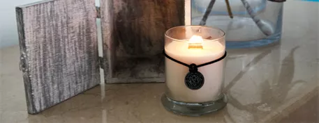 Vela con pabilo de madera encendida sobre una superficie de madera rústica